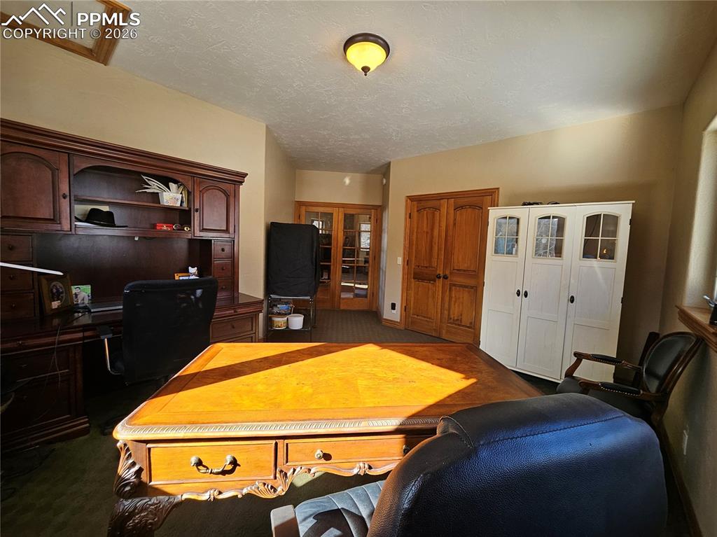 Image 11 of 48: Office featuring dark colored carpet, French doors, with a closet