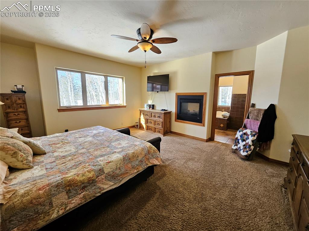 Image 12 of 48: Main level primary bedroom with see-through fireplace to adjoining primary 