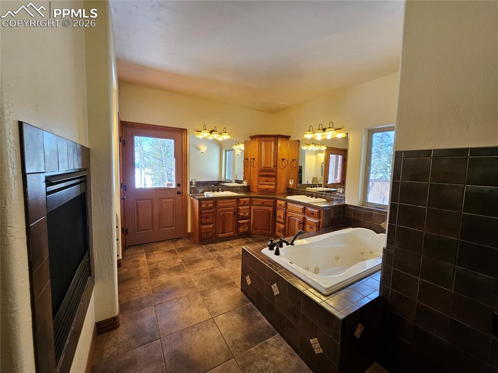 Image 13 of 48: Primary bathroom with two vanities, a jetted tub, healthy amount of natural