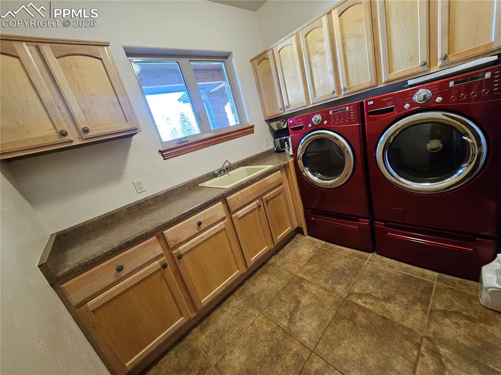 Image 16 of 48: Laundry area featuring separate washer and dryer, cabinet space, and dark t