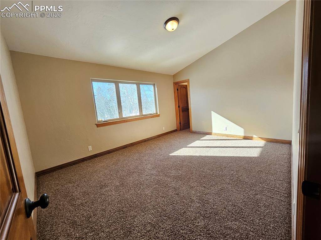 Image 19 of 48: Carpeted bedroom upstairs with vaulted ceiling and walk-in closet