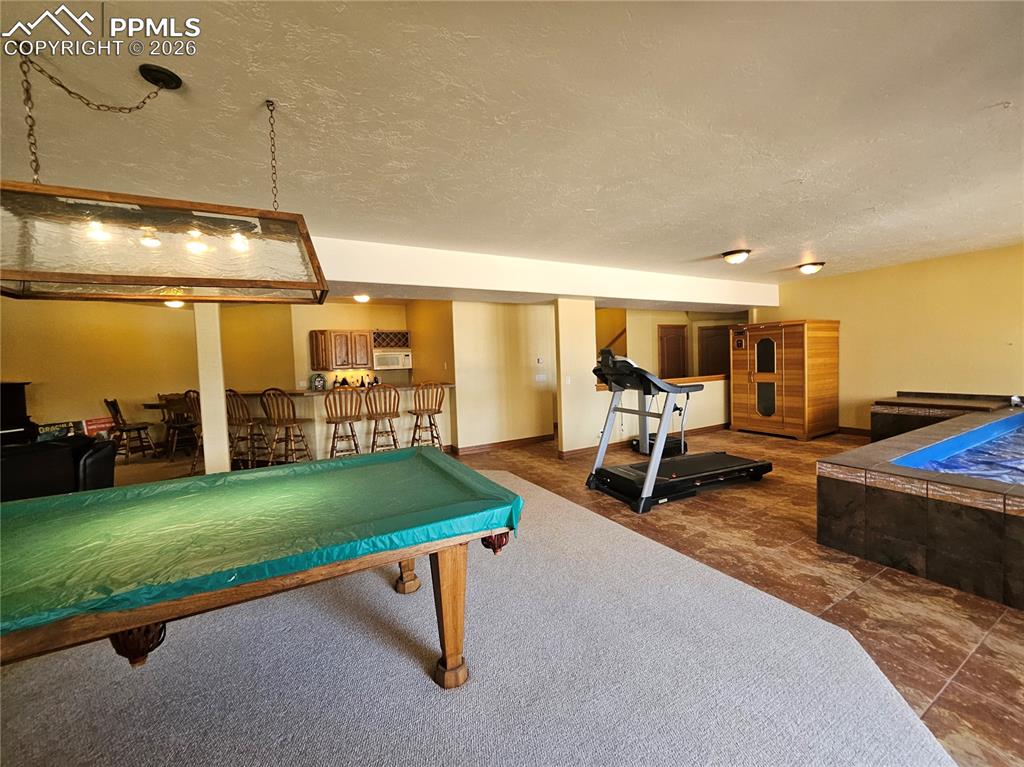 Image 24 of 48: Game room with pool table, 6-seat bar, and indoor endless pool