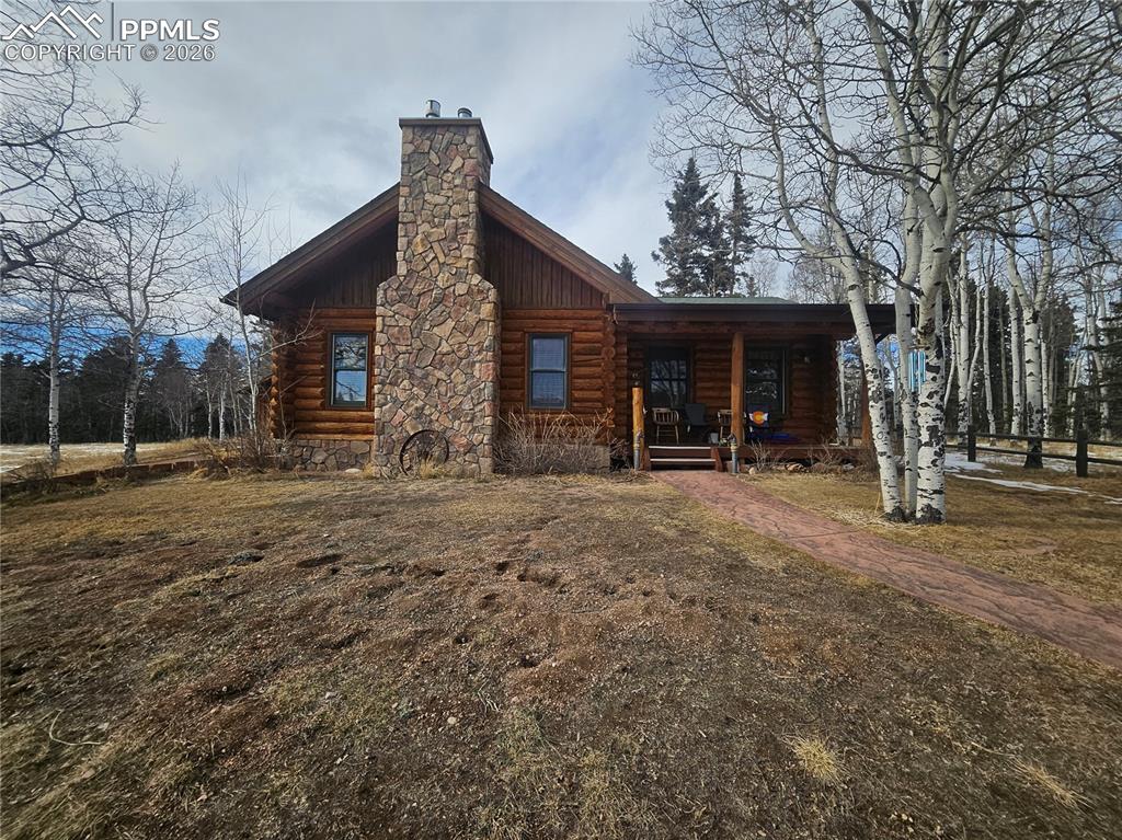 Image 30 of 48: The cabin  with log exterior, covered porch, and a stone chimney