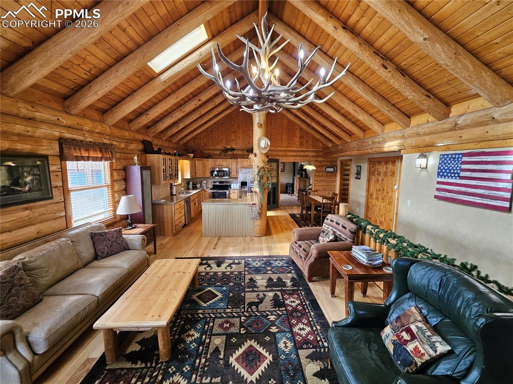 Image 31 of 48: Cabin living area featuring log walls, suspended lighting, light wood-type 
