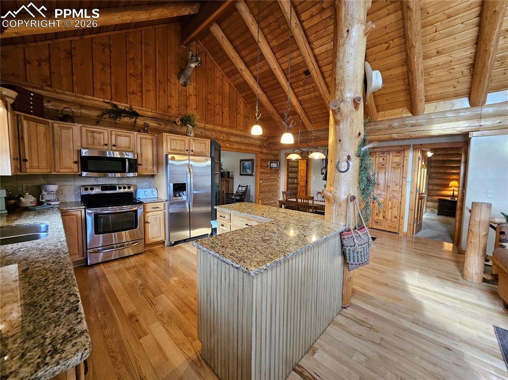 Image 33 of 48: Cabin kitchen featuring log walls, stainless steel appliances, a high woode
