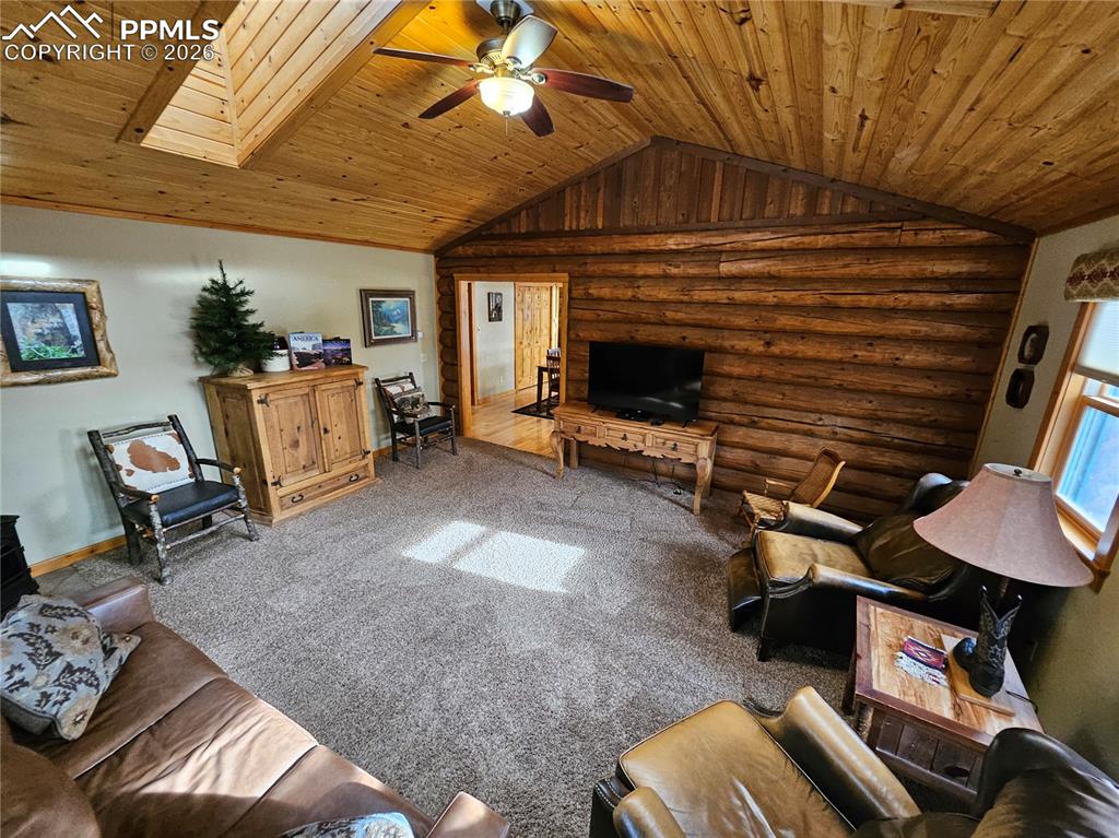 Image 36 of 48: Living area featuring rustic walls, a ceiling fan, carpet flooring, and woo
