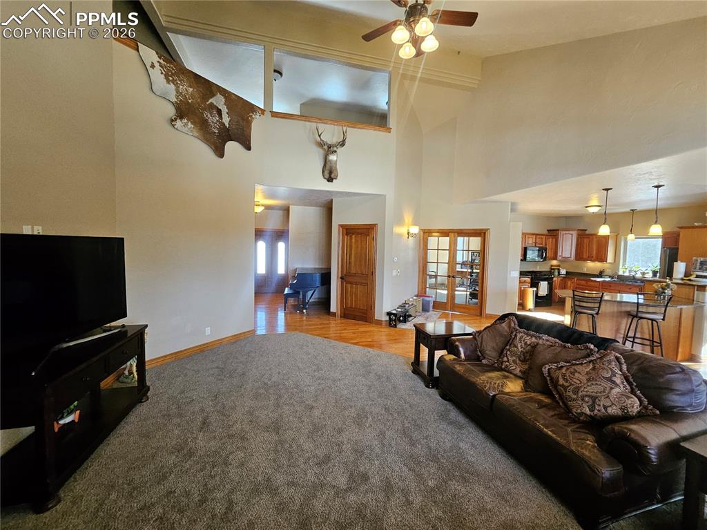 Image 4 of 48: Living area with French doors, light colored carpet, ceiling fan, plenty of