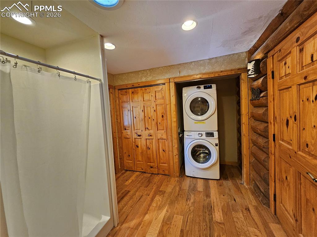 Image 41 of 48: Cabin laundry area featuring hardwood / wood-style flooring, stacked washin