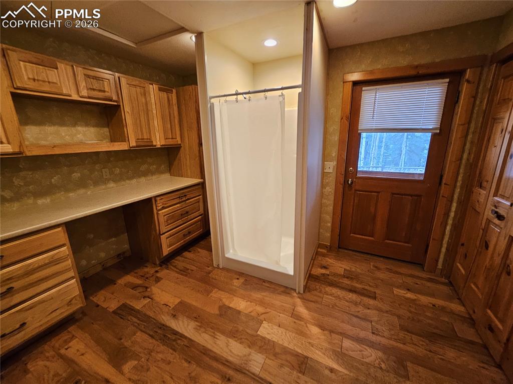 Image 42 of 48: Cabin laundry room featuring a stall shower, dark wood finished floors, clo