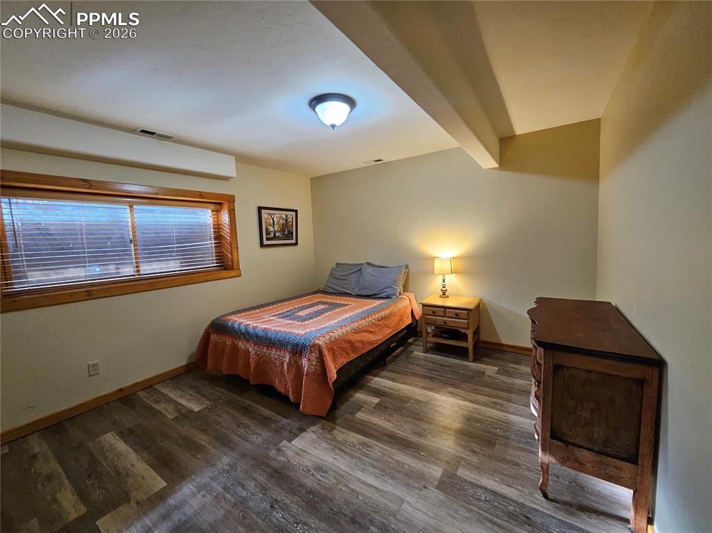 Image 44 of 48: Cabin bedroom in basement featuring beam ceiling and dark wood-style floori