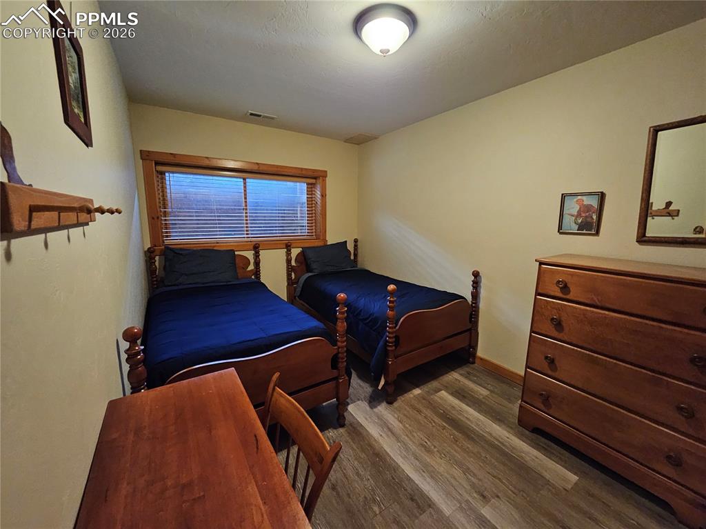 Image 46 of 48: Bedroom with dark wood-style floors in cabin basement