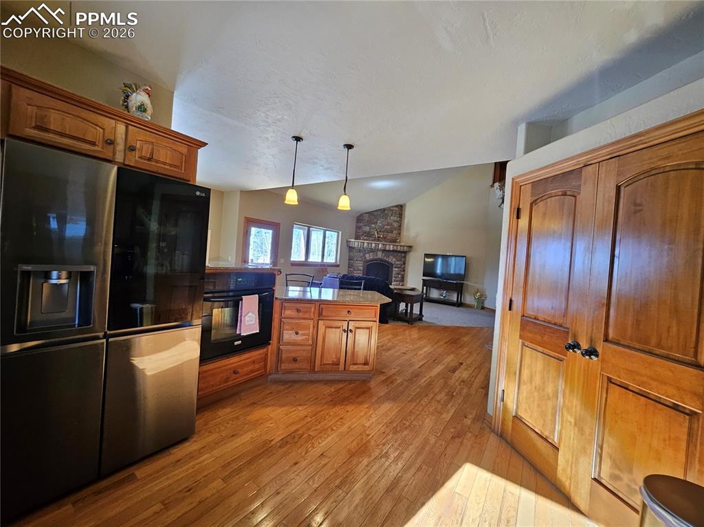 Image 8 of 48: Kitchen featuring black appliances, wood finish cabinets, lofted ceiling, p