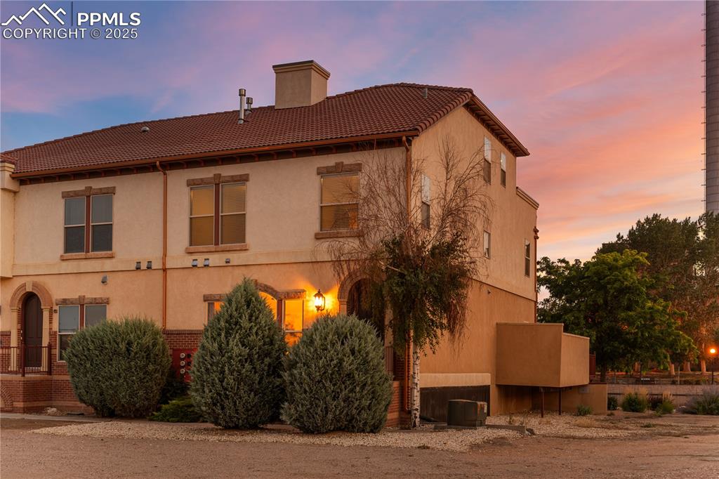 Image 30 of 34: View of property exterior featuring a chimney, a tile roof, and stucco sidi