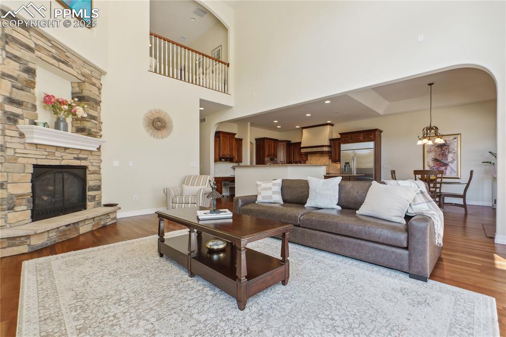 Image 10 of 41: Living area with wood finished floors, a high ceiling, baseboards, a stone