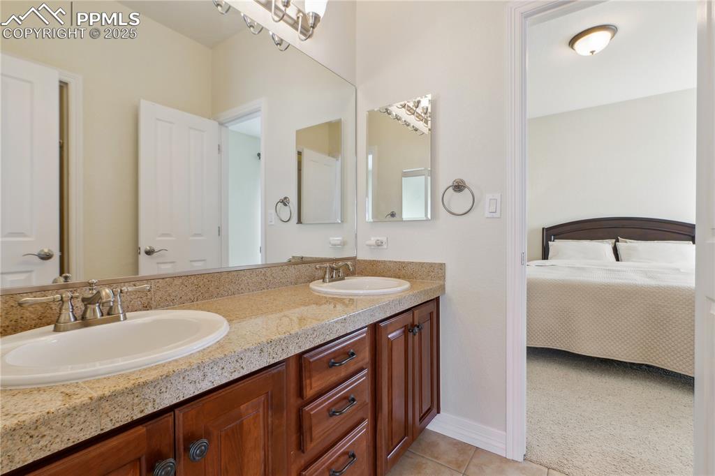 Image 24 of 41: Ensuite bathroom with a sink, tile patterned flooring, double vanity, and e
