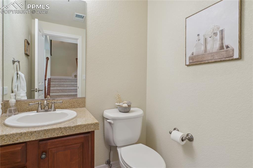 Image 32 of 41: Half bathroom with toilet, vanity, and visible vents