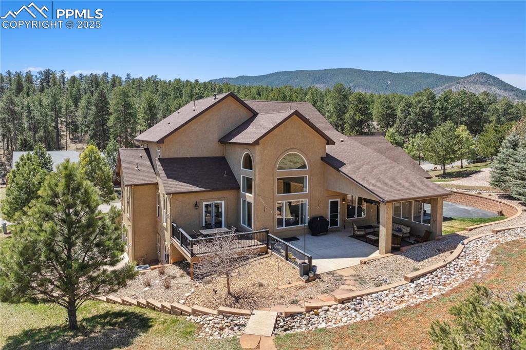 Image 36 of 41: Rear view of house featuring a mountain view, stucco siding, a forest view,