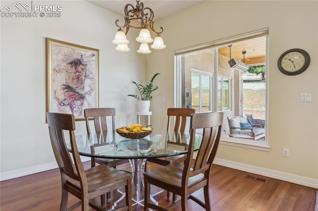 Image 8 of 41: Dining area featuring a chandelier, wood finished floors, baseboards, and v