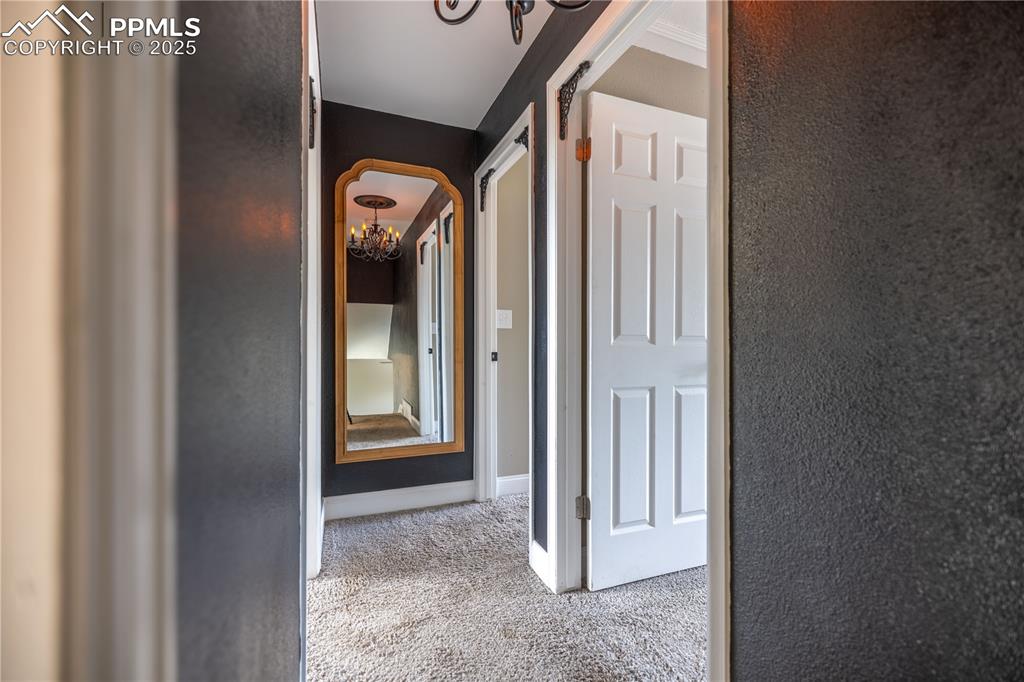 Image 12 of 28: Upper level Hallway with a chandelier, carpet flooring, and arched walkways