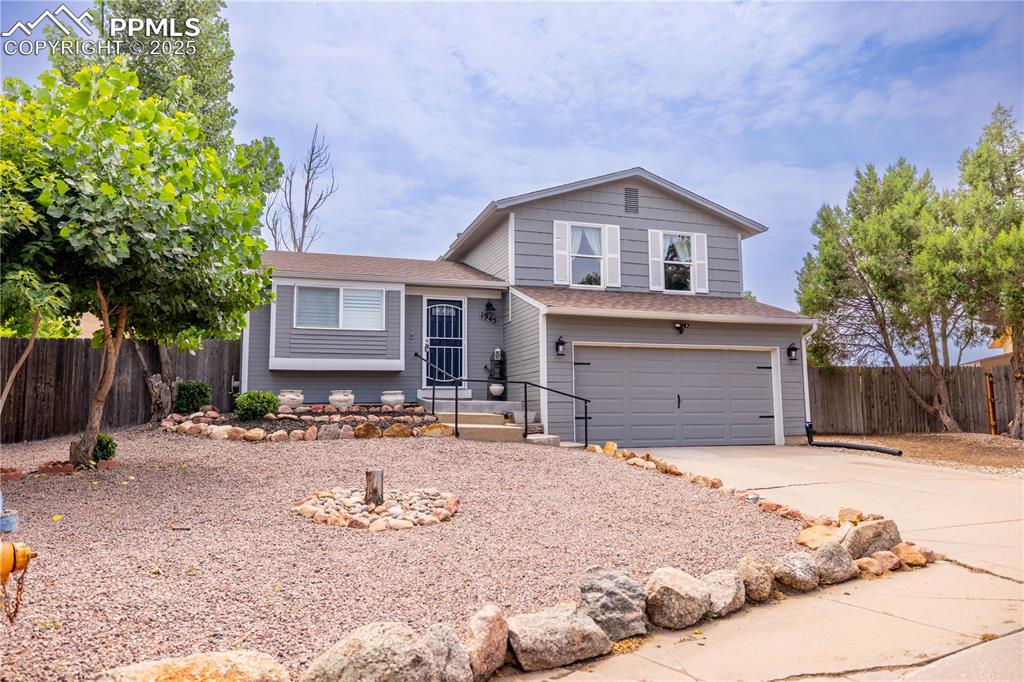 Image 2 of 28: Split level home featuring large driveway, 2 car garage, and xeriscaped yar