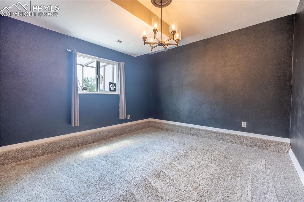 Image 22 of 28: Lower level flex space, room with a chandelier and baseboards; window provi