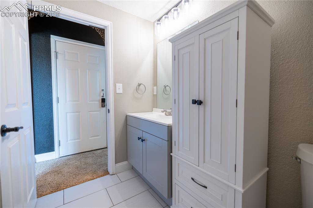 Image 25 of 28: Lower level Half bathroom with vanity and tile patterned floors