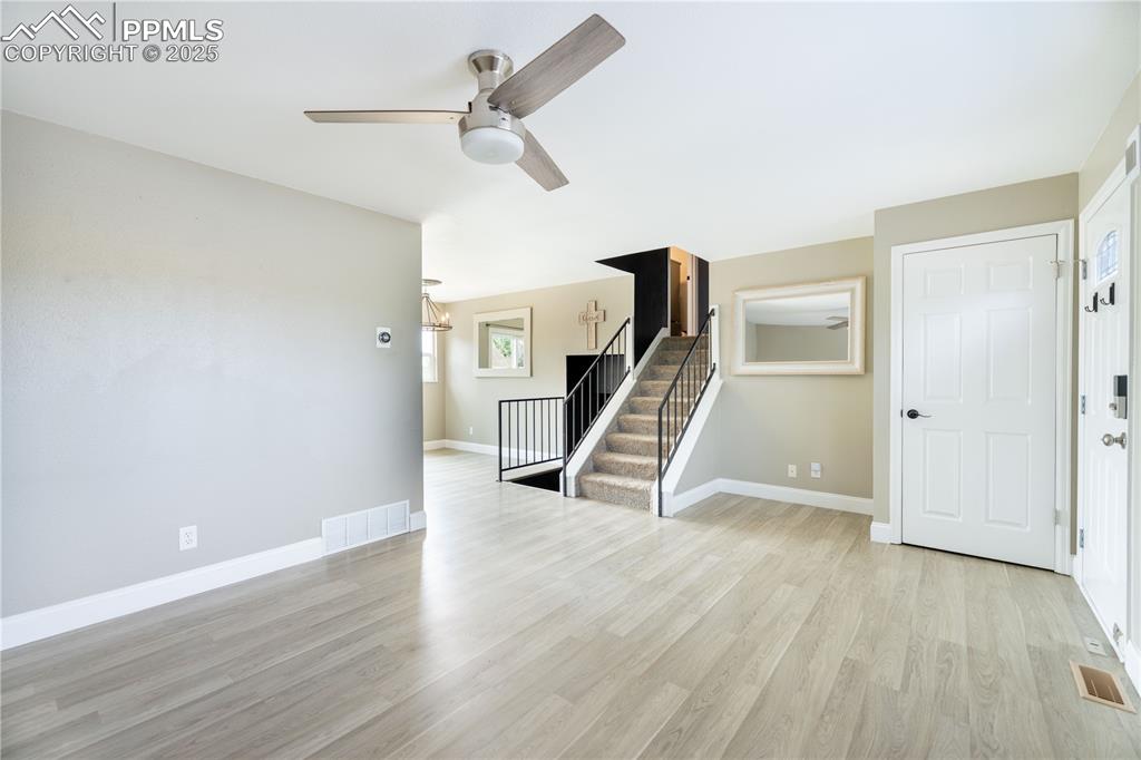 Image 5 of 28: Unfurnished living room with light wood-type flooring, ceiling fan, and sta