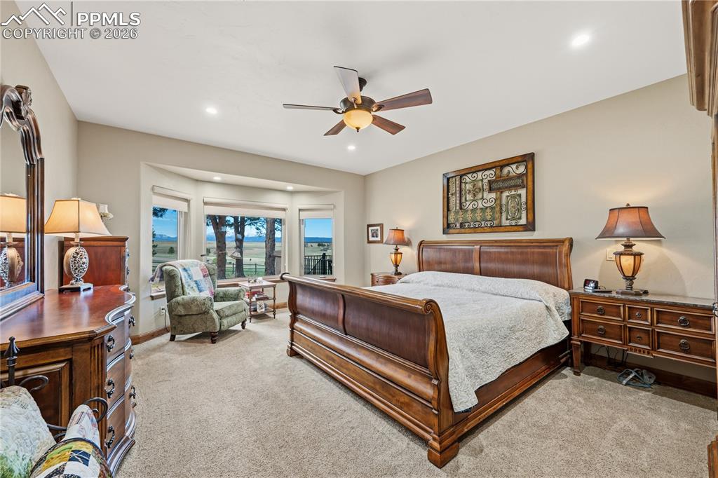 Image 16 of 45: Spacious primary bedroom with bay window framing Peak & mountain views