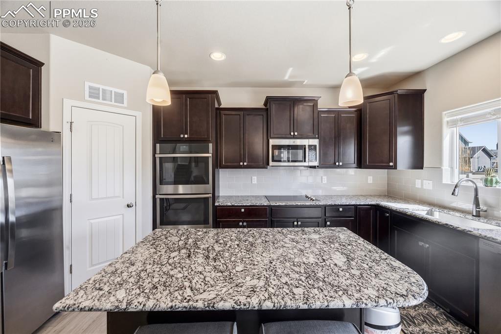 Image 16 of 41: The Kitchen features a large island, pantry, wood cabinetry with granite co