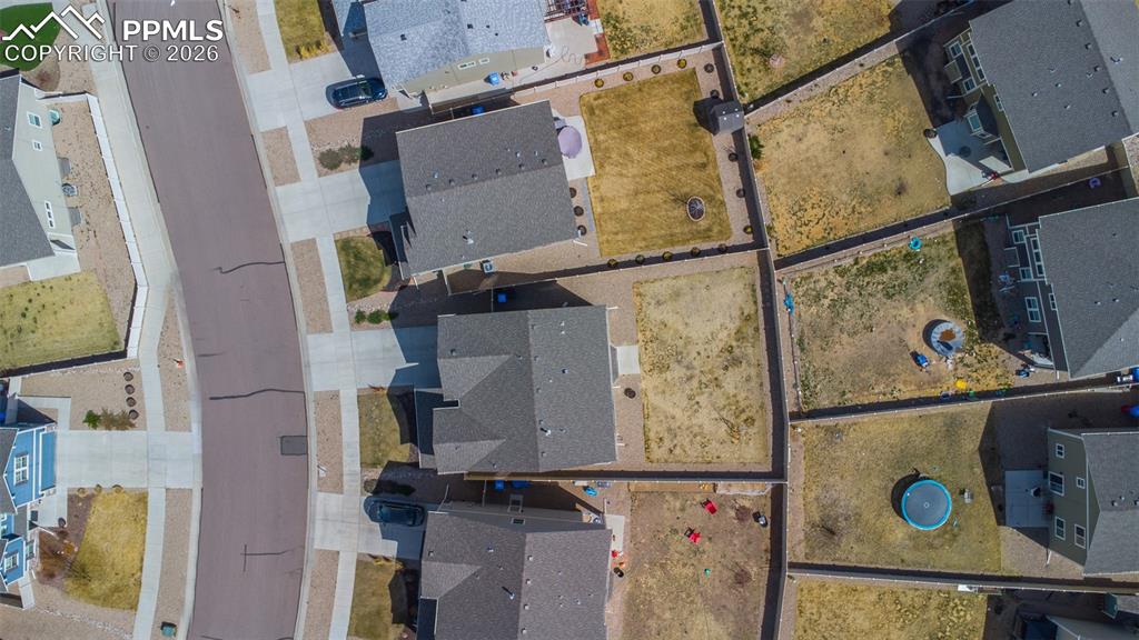 Image 38 of 41: Fenced, xeriscaped backyard with concrete patio, grass area, and rock beds.