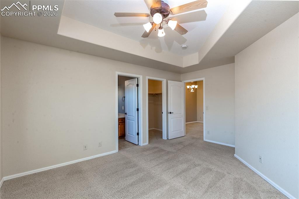 Image 15 of 23: Carpet in primary bedroom with ceiling fan and tray ceilings