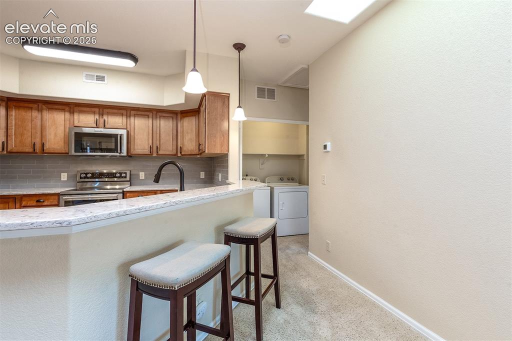 Image 16 of 23: Laundry conveniently located just around the corner from the kitchen, next