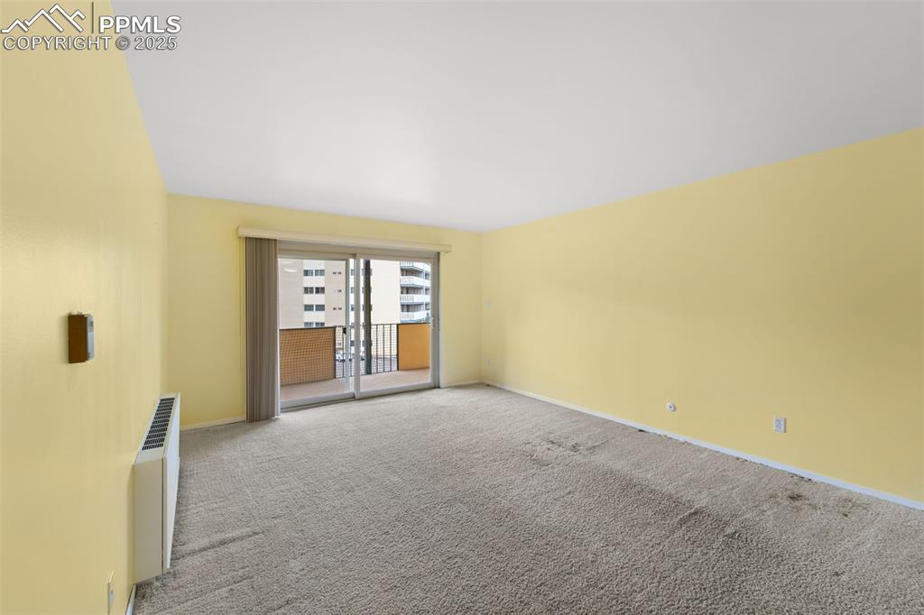 Image 11 of 23: Carpeted spare room featuring baseboards and radiator