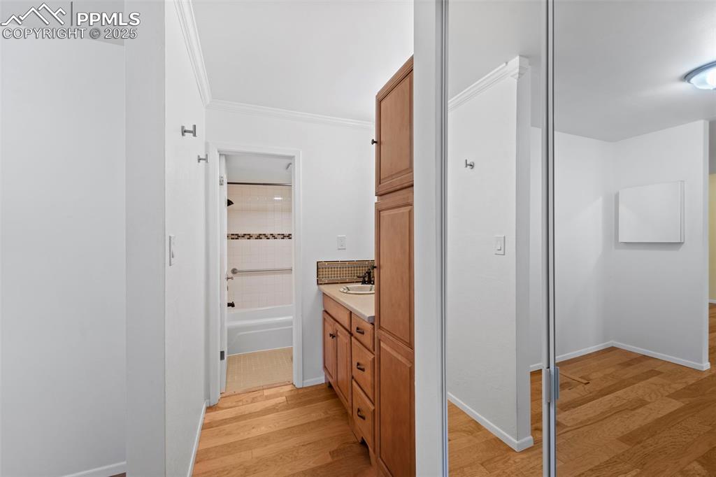 Image 16 of 23: Bathroom featuring wood finished floors, vanity, ornamental molding, and ba