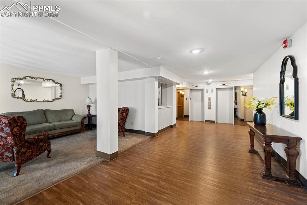 Image 23 of 23: Living area with dark wood-style flooring and elevator