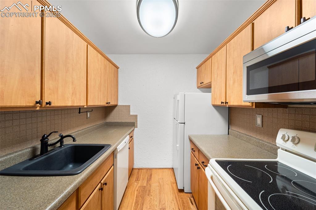 Image 7 of 23: Kitchen featuring white appliances, light wood-type flooring, and tasteful