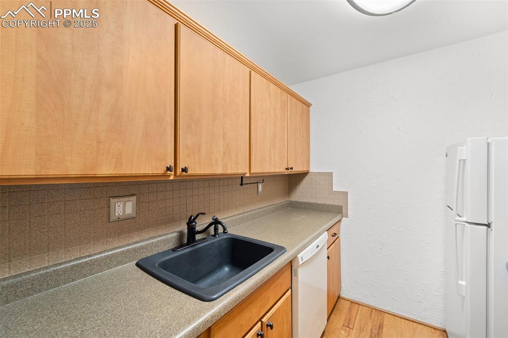 Image 9 of 23: Kitchen featuring white appliances, backsplash, light wood finished floors,