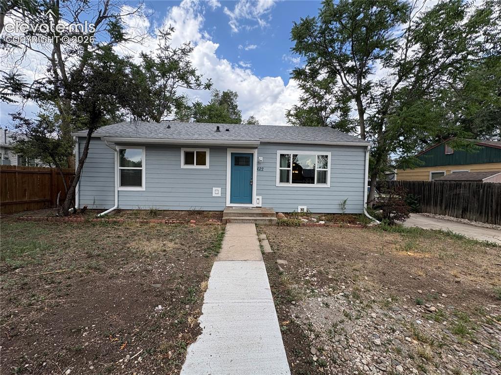 Image 1 of 12: Light blue siding exterior with white trim windows and a vibrant blue entry