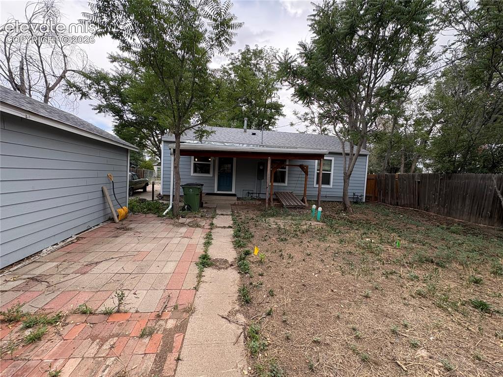 Image 12 of 12: Rear exterior featuring a covered porch, wood plank siding, and a fenced pe