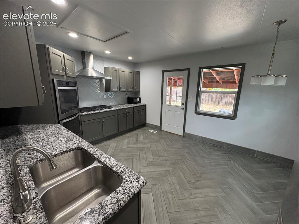 Image 4 of 12: Kitchen featuring stainless steel appliances, dark cabinetry, light counter