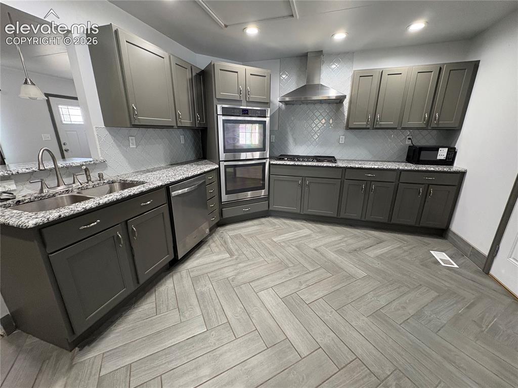 Image 5 of 12: Herringbone-pattern wood-finish flooring, grey cabinetry with silver hardwa