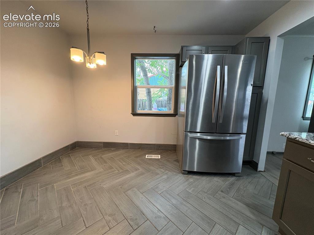 Image 6 of 12: Modern chandelier, window with dark trim, stainless steel refrigerator, gre
