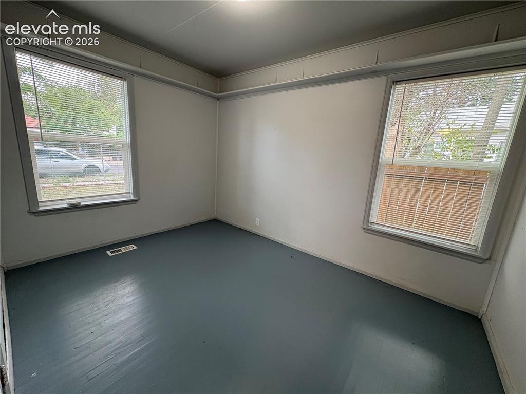 Image 9 of 12: Painted wood flooring, two windows with blinds, and white walls