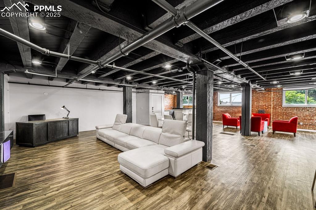 Image 12 of 32: Living area featuring brick wall and wood finished floors