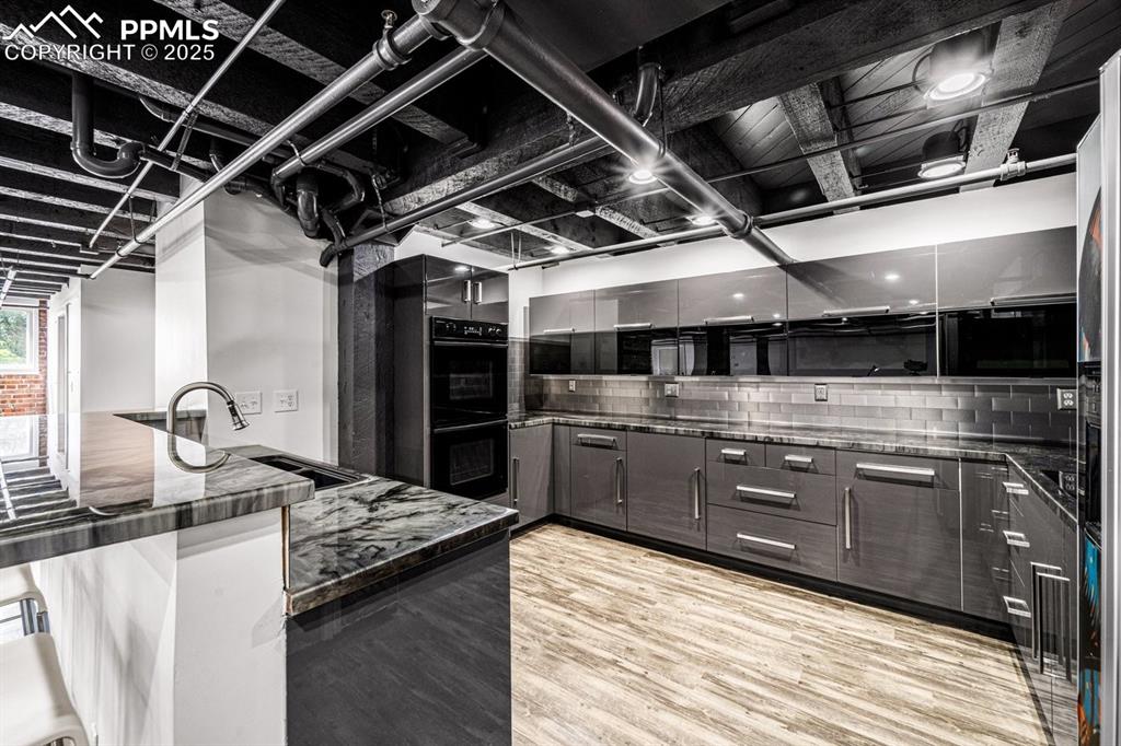 Image 13 of 32: Kitchen featuring light wood-style floors, decorative backsplash, modern ca
