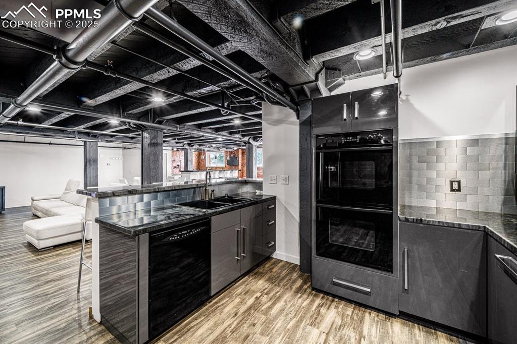 Image 14 of 32: Kitchen featuring black appliances, wood finished floors, a breakfast bar a