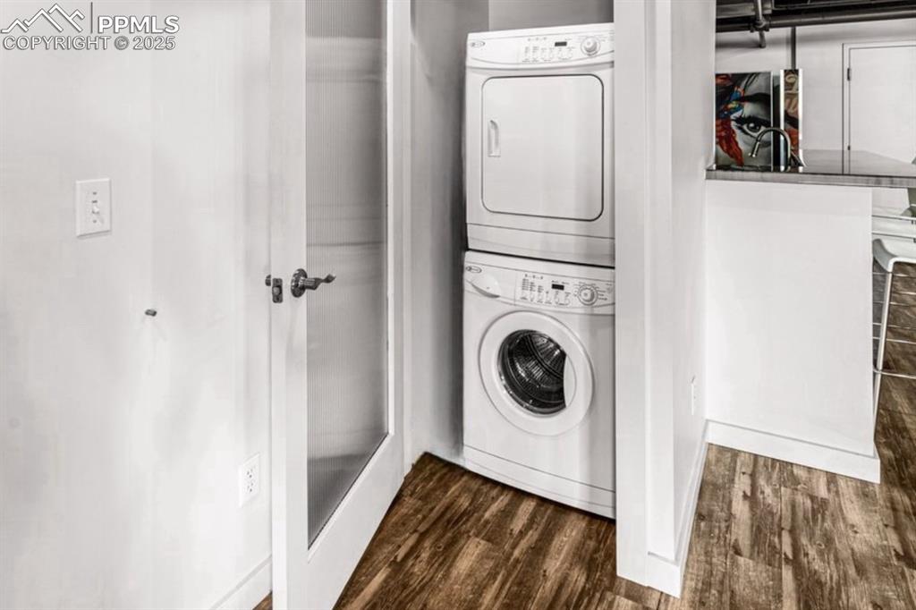 Image 17 of 32: Laundry area featuring stacked washer / drying machine and dark wood-type f