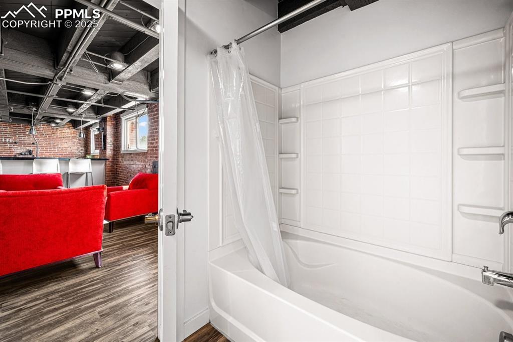 Image 20 of 32: Full bath with brick wall, shower / bath combo with shower curtain, and woo