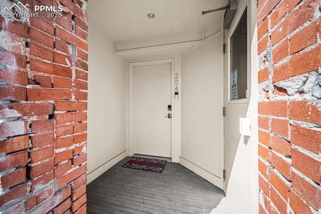 Image 3 of 32: Doorway to property featuring brick siding