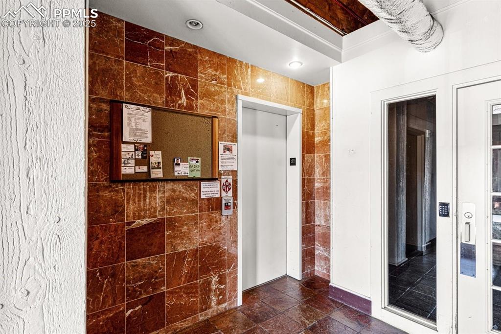 Image 31 of 32: Corridor with tile walls and elevator
